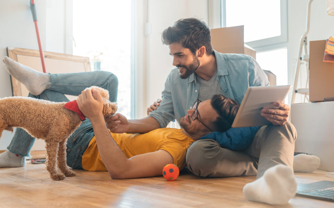 Male couple unpacking with a dog